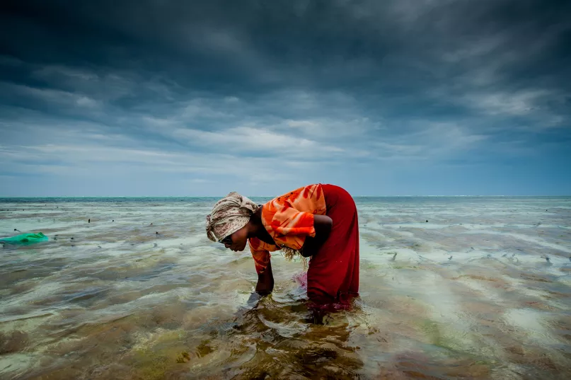 Une femme fouille le sable en Tanzanie.