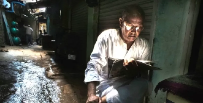 Man reading newspaper in alley. Photo by Rana Pandey, 2015 CGAP Photo Contest.