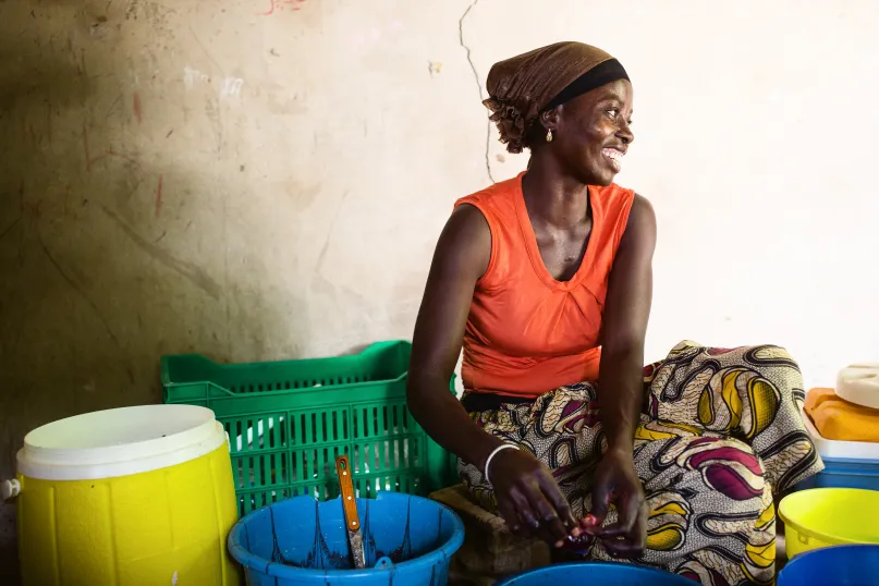 A woman sits among buckets and smiles