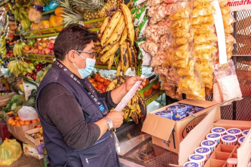 Hombre de perfil usando tapabocas, en el interior de un pequeño comercio en Perú.