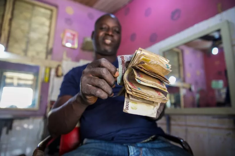 Mobile money agent counting banknotes in store in Nigeria.
