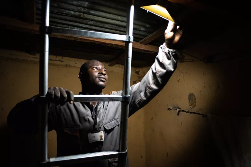Engineer adjusting a lamp from a solar kit, Mali.