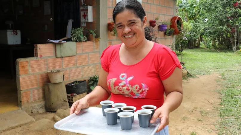 Una mujer colombiana sonriendo y con café.