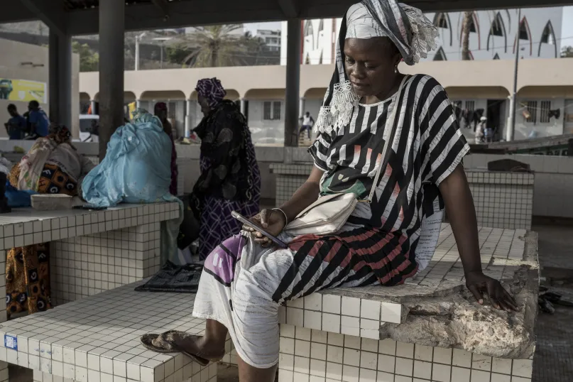 Une femme achète du poisson avec le mobile money à Dakar au Sénégal.