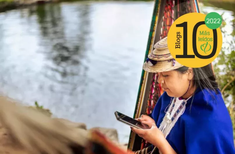 Joven mujer usando su teléfono móvil junto al agua en Cauca, Colombia, logo Portal FinDev.