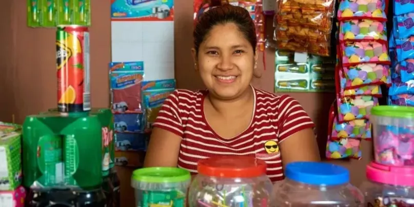Una mujer sonríe detrás de mostrador de su micronegocio en México.