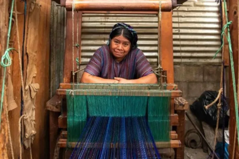 Mujer de frente, inclinada sobre un telar en Guatemala.