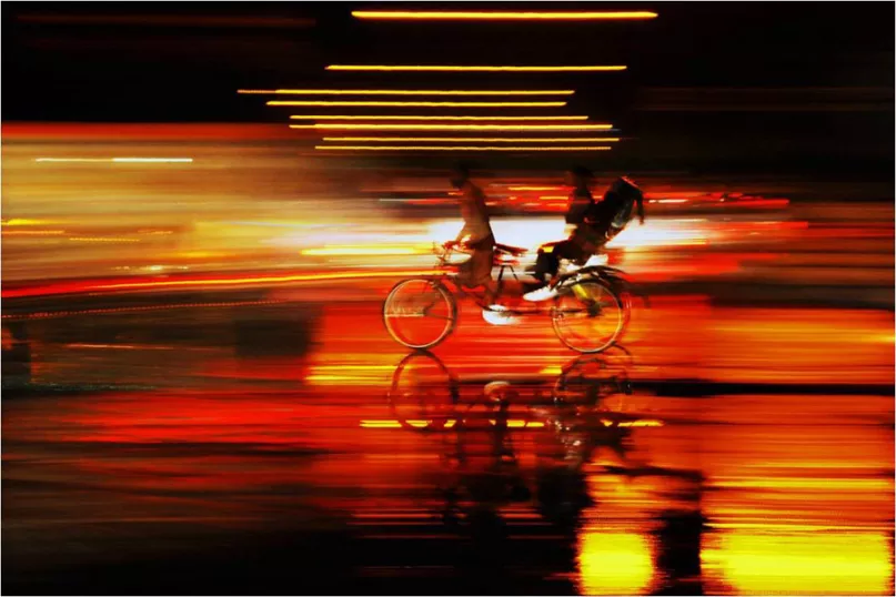 Blurry artistic photo of someone riding a bicycle with a child sitting in the back