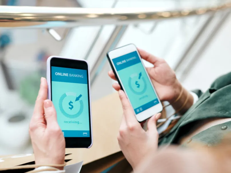 شخصان يحولان الأموال عبر الإنترنت باستخدام تطبيقات الهاتف المحمول لإرسال الأموال وتلقيها.