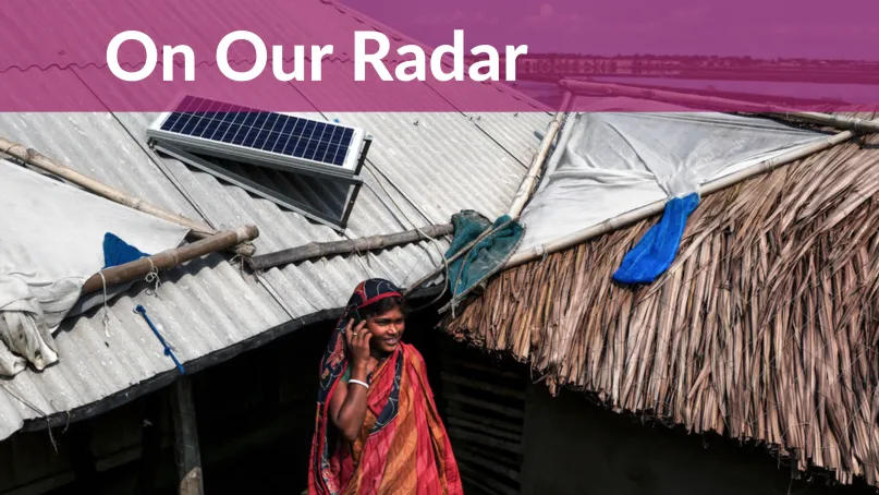 Woman talks on phone under rooftop solar panel.