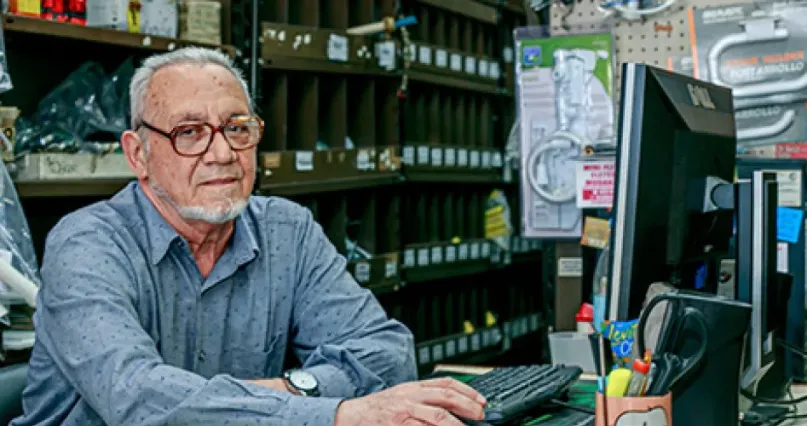 Hombre trabajando en computadora en su negocio en Argentina.