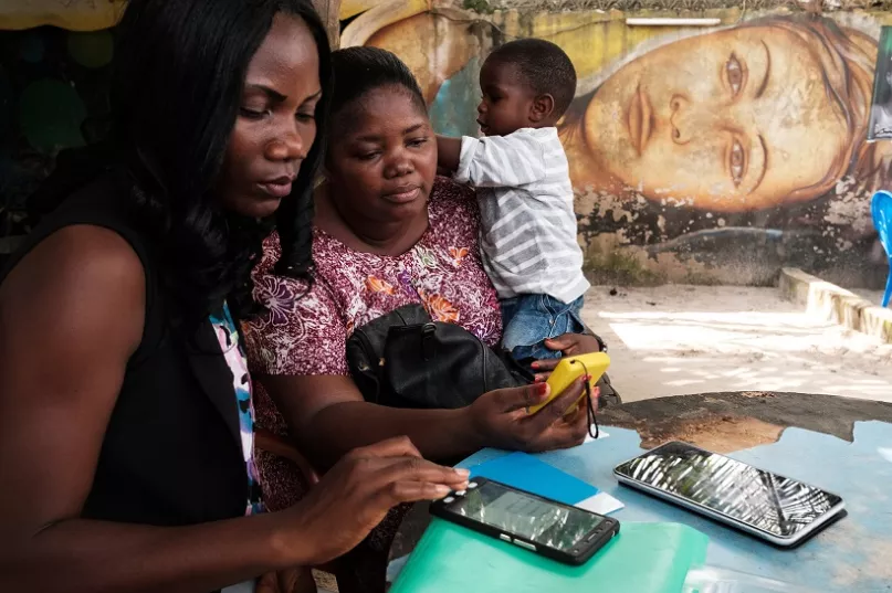 Deux jeunes femmes utilisant un appareil de paiement mobile à Abidjan en Côte d’Ivoire. Photo : © Nyani Quarmyne/IFC