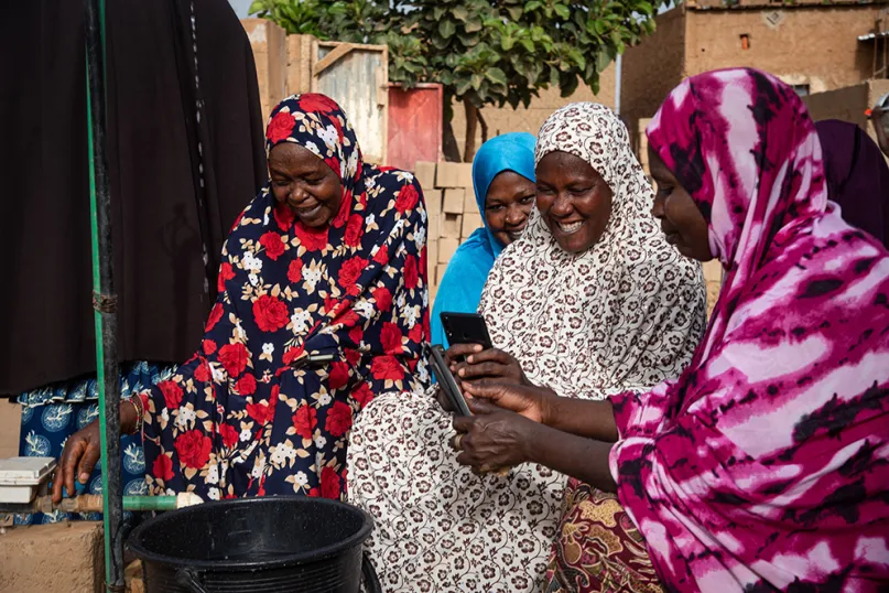 Groupe de femmes assises à côté d'une borne fontaine au Niger.