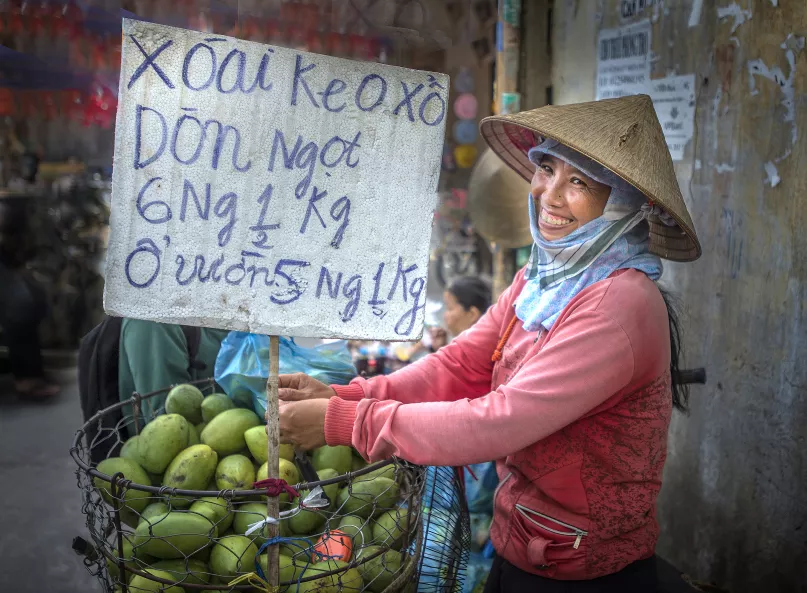 A fruit vendor smiles near her stand on the street
