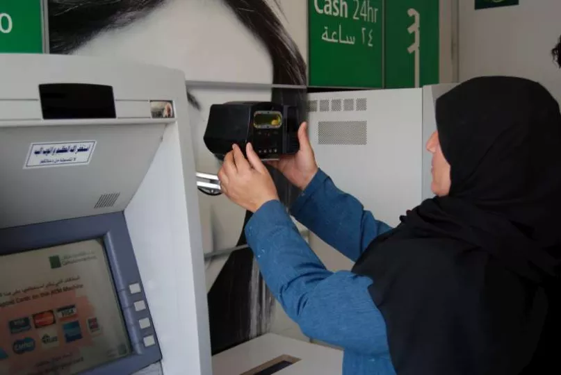لاجئة سورية تستخدم بصمة العين لسحب نقودها من جهاز الصرف الآلي في عمان، الأردن. UNHCR.