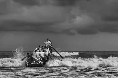 A group of fishermen on a boat fighting waves, India.