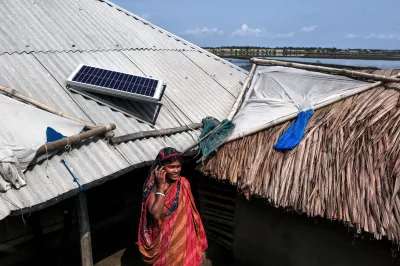Woman with a mobile phone standing in front of a house with solar panel.