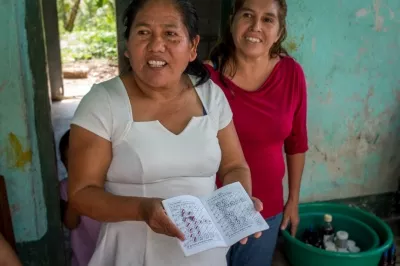 Dos mujeres mostrando su libreta de ahorros en una casa en México.