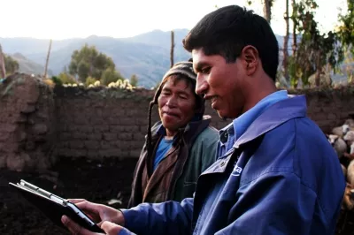 Dos hombres mirando una tablet en una zona rural en Perú.