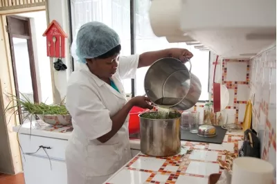 Mujer vertiendo agua en una olla para elaborar jabón en Haití.