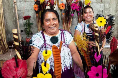 Dos mujeres sonríen entre sus flores artesanales en México.