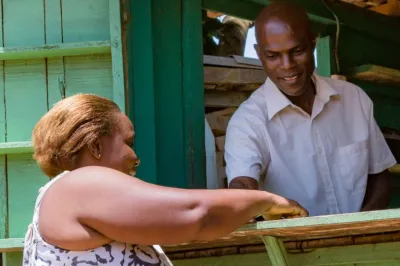 Male mobile money agent helping a woman customer.