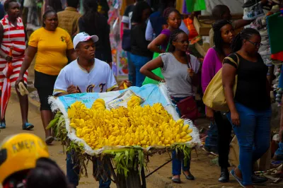 Un homme pousse un chariot rempli de bananes au Kenya.