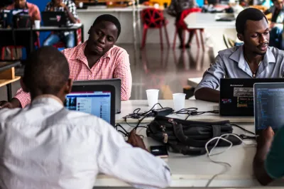 Three men sitting at a table working on computers.