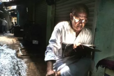 Man reading newspaper in alley. Photo by Rana Pandey, 2015 CGAP Photo Contest.