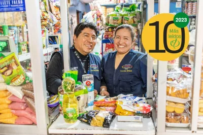 Una mujer y un hombre sonríen a la cámara en entre mercadería en un almacén en Lima, Perú.