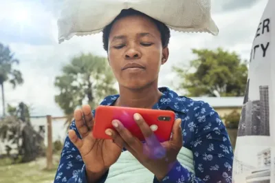 Mujer con una bolsa en su cabeza, mirando y tocando un teléfono móvil.