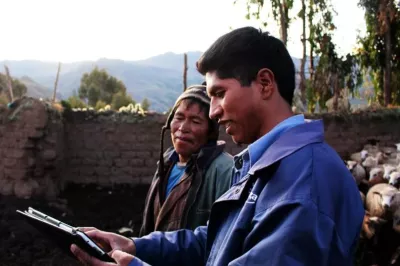 Un hombre joven y un hombre mayor miran una tableta en un entorno rural en Perú.