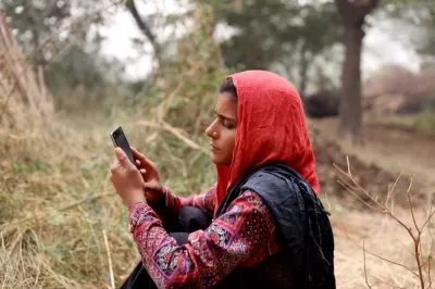 Woman holding cell phone, India.