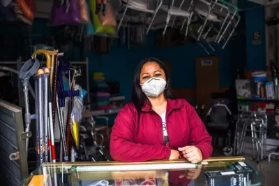 Mujer con tapabocas ante el mostrador de su pequeña empresa en Perú.