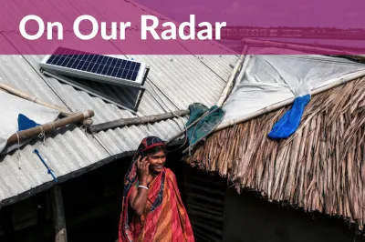 Woman talks on phone under rooftop solar panel.