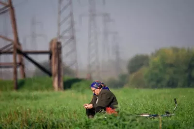 Mujer sentada en un campo junto a su bicicleta usando el teléfono móvil, en Bielorusia.