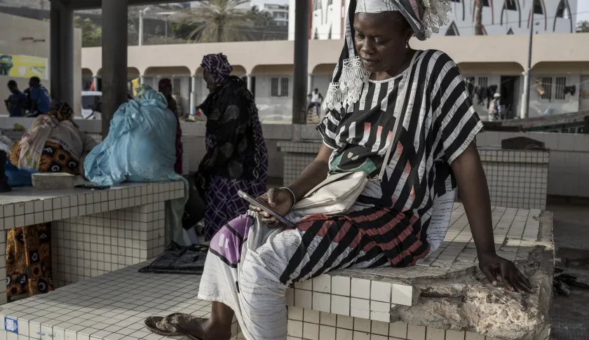 Une femme achète du poisson avec le mobile money à Dakar au Sénégal.