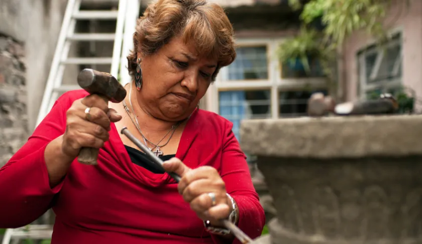 Mujer microempresaria tallando en talabera en México.