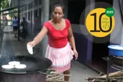 Una mujer colocando una pupusa en una sartén en El Salvador.
