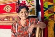 Mujer sentada delante de artesanías textiles en México.