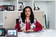 Roshaneh Zafar of Kashf Foundation in Pakistan, sitting at a desk with shelves behind her.