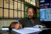 Mujer escribiendo a mano en un libro en una oficina en Nigeria.