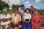 A group of women looking into a device smiling.