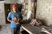 Hombre parado con zapatos en la mano en su taller de calzado artesanal en México.