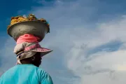 Mujer vista de espalda con una vasija de cocadas en su cabeza en Colombia.