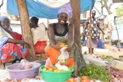 Woman sorting tomatoes for her customer at the marketplace. Photo credit: VisionFund International 2019.