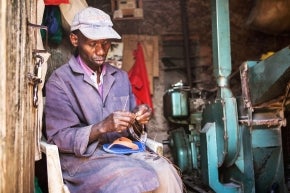 Un homme réparant une sandale dans son atelier, Kenya.