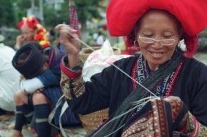 Mujer sonriendo mientras borda textiles en Vietnam.