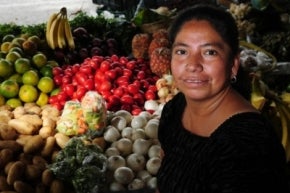 Mujer ante su puesto de frutas y verduras en Guatemala.