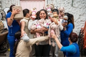 Mujeres abrazándose entre muñecos tejidos en México.